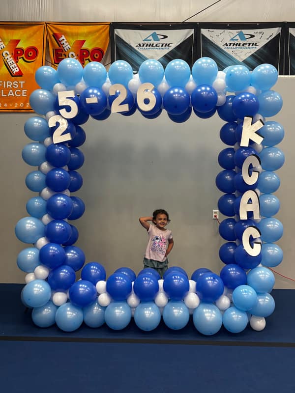 Large square blue and white balloon photo frame with KCAC 25-26 lettering for an athletics team photo station