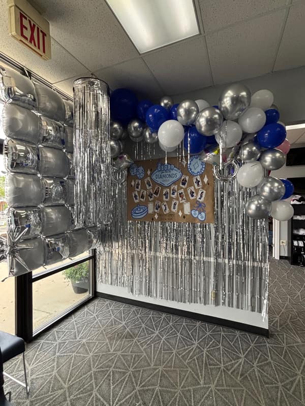Blue, silver and white balloon garland with silver foil fringe backdrop for a Diamonds cheer team event